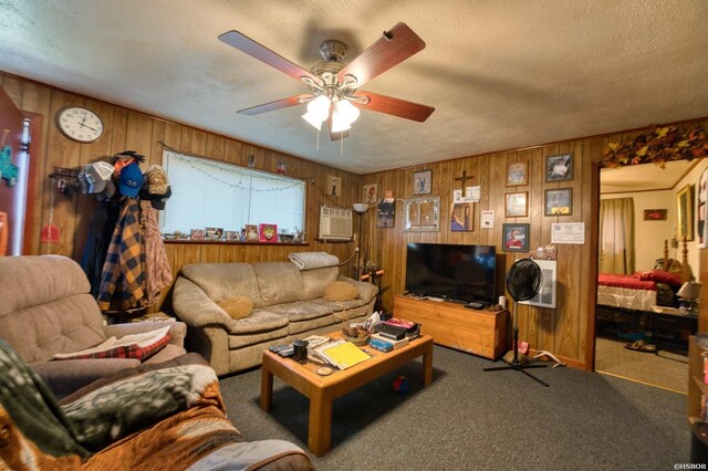 carpeted living area featuring a textured ceiling, ceiling fan, and wood walls