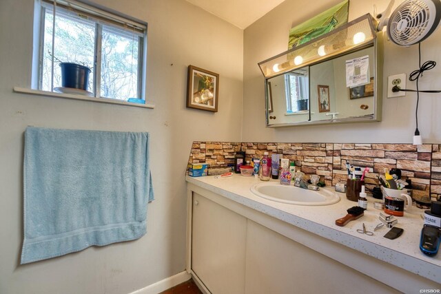 bathroom featuring tasteful backsplash, vanity, and baseboards