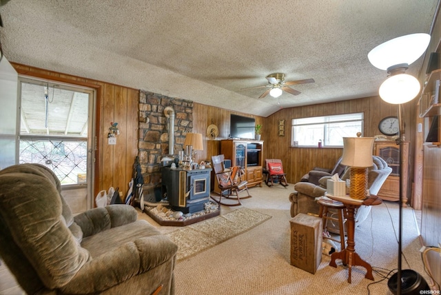 living area with a wood stove, carpet flooring, wood walls, and a textured ceiling