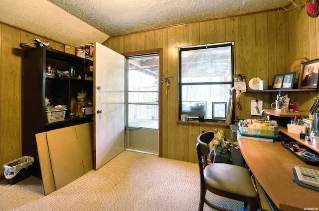 office space with light carpet, wooden walls, and a textured ceiling