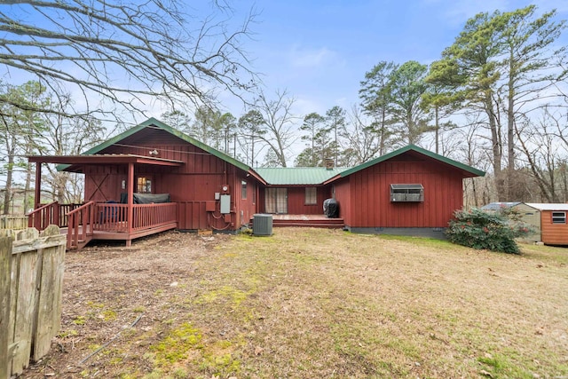 rear view of property featuring a lawn, metal roof, crawl space, a storage unit, and central air condition unit