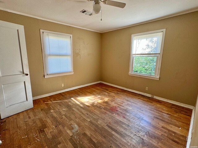 unfurnished room featuring baseboards, wood finished floors, visible vents, and crown molding