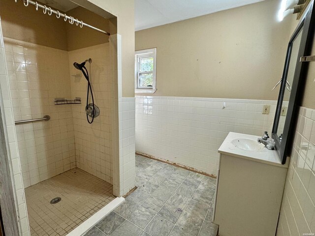 full bath with a wainscoted wall, a stall shower, vanity, and tile walls