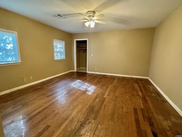 unfurnished room featuring baseboards, visible vents, ceiling fan, and dark wood-type flooring