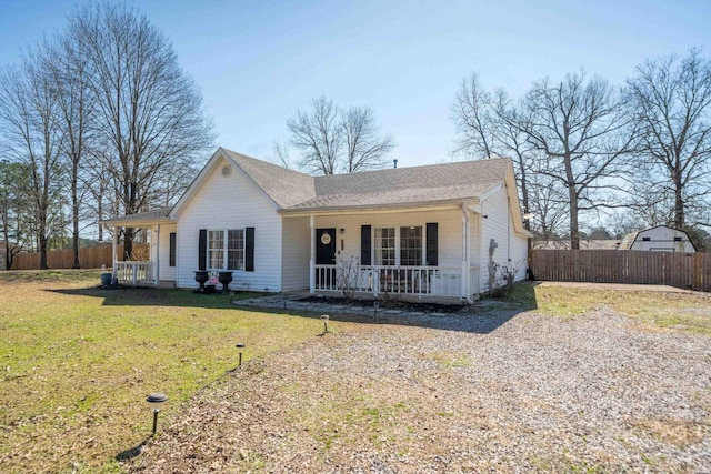 single story home featuring gravel driveway, covered porch, a front lawn, and fence