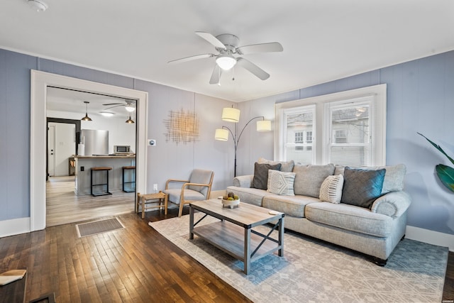 living area with visible vents, wood finished floors, a ceiling fan, and baseboards