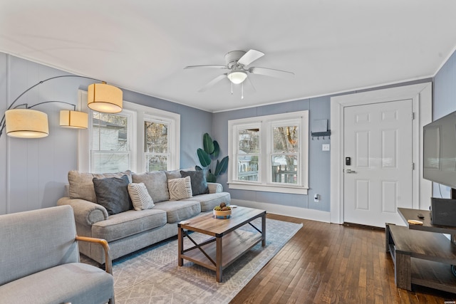 living room featuring a ceiling fan, dark wood-style flooring, ornamental molding, and baseboards