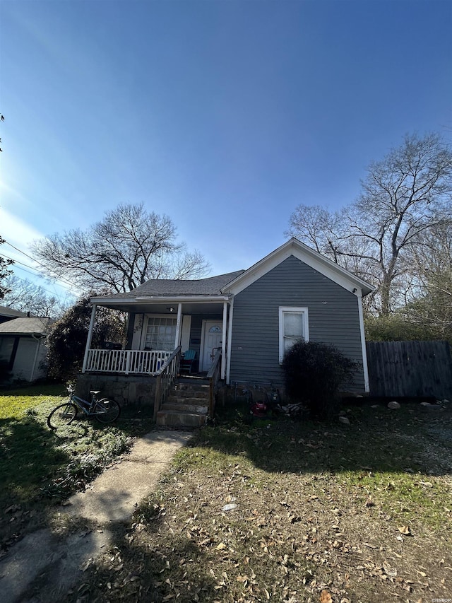 view of front of property featuring a shingled roof, fence, and a porch