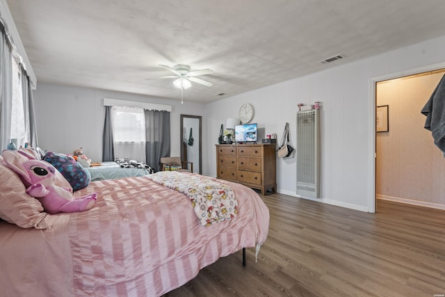 bedroom featuring ceiling fan, wood finished floors, visible vents, and baseboards