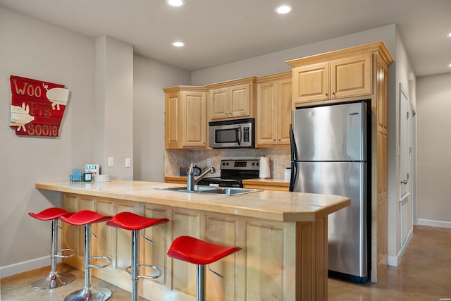 180 Port Au Prince, Hot Springs, AR 71913 - kitchen featuring stainless steel appliances, light brown cabinetry, baseboards, a sink, and a kitchen bar