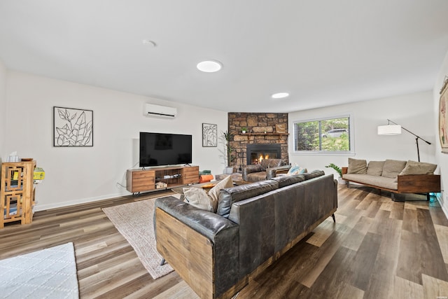 340 Vanadium Cir, Hot Springs, AR 71901 - living room featuring baseboards, a wall mounted AC, a stone fireplace, and wood finished floors