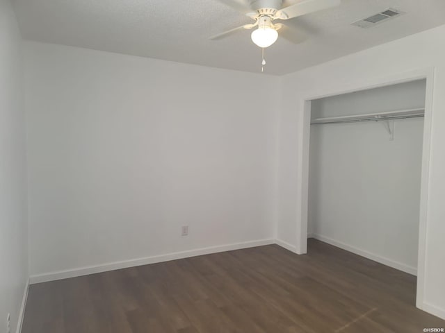 unfurnished bedroom featuring dark wood-style flooring, a closet, visible vents, and baseboards