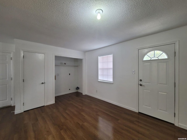 foyer entrance with a textured ceiling, baseboards, dark wood-style flooring, and a wealth of natural light