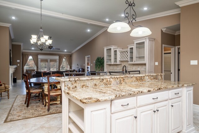 kitchen with glass insert cabinets, white cabinets, hanging light fixtures, french doors, and a center island with sink