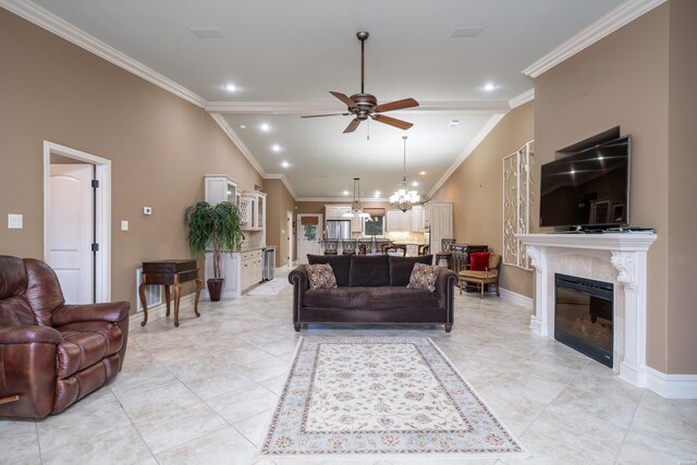 living room with ceiling fan with notable chandelier, ornamental molding, a fireplace, and baseboards