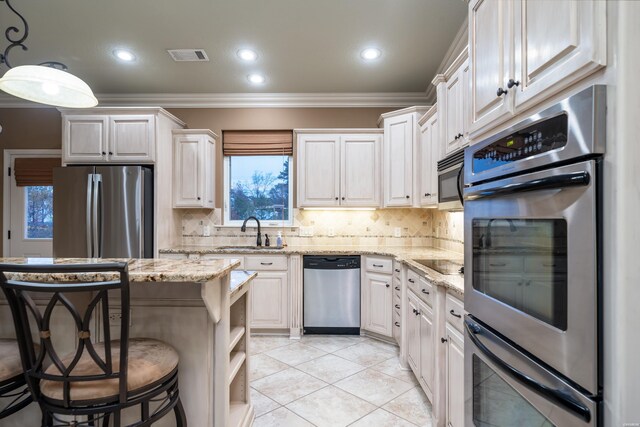 kitchen featuring hanging light fixtures, light stone counters, stainless steel appliances, and a sink