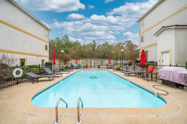 pool featuring a patio area, fence, and grilling area