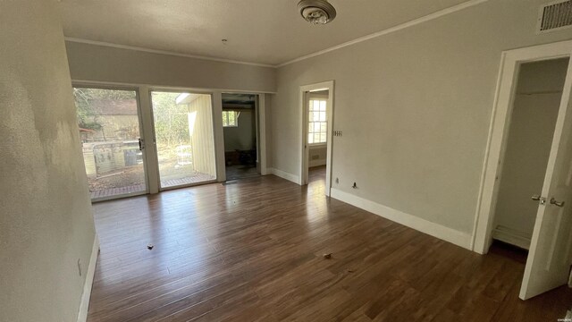 interior space featuring baseboards, visible vents, dark wood-style flooring, and ornamental molding