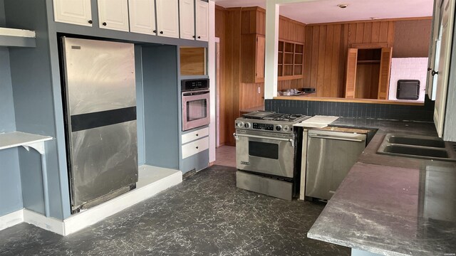 kitchen featuring tasteful backsplash, dark countertops, appliances with stainless steel finishes, white cabinets, and a sink