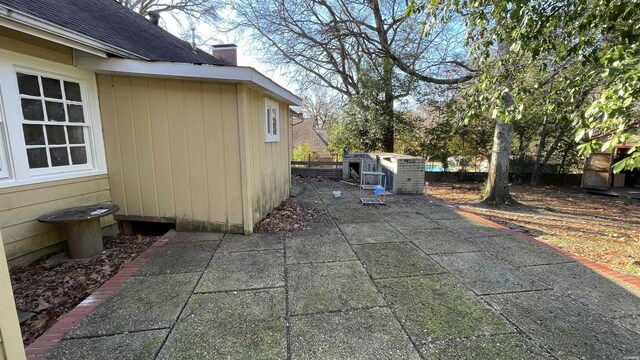 view of property exterior with a shingled roof, a patio, and a chimney