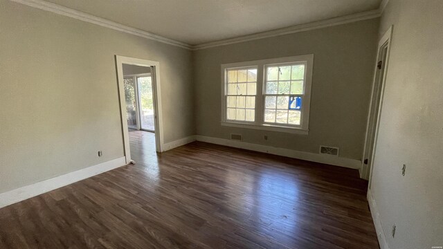 spare room with visible vents, crown molding, baseboards, and dark wood-type flooring