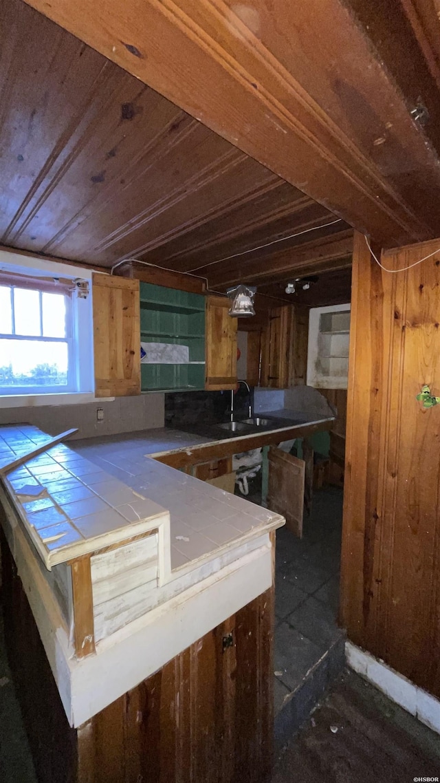 kitchen with wood ceiling, tile counters, and a sink