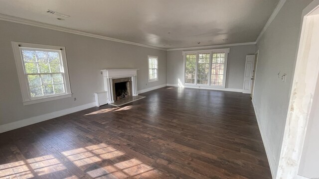 unfurnished living room featuring dark wood-style floors, ornamental molding, a premium fireplace, and plenty of natural light