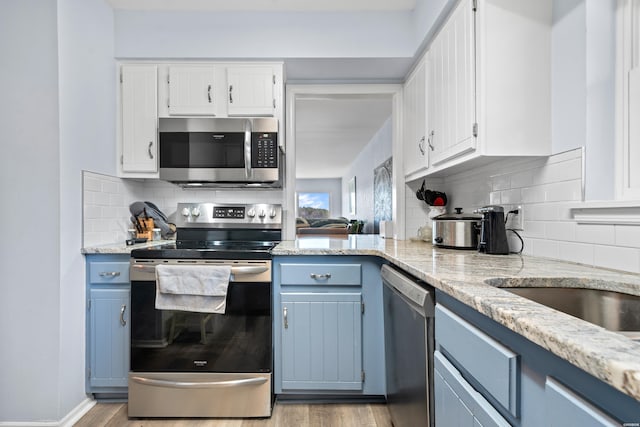 kitchen with appliances with stainless steel finishes, blue cabinetry, and white cabinets