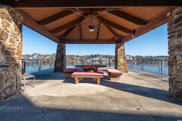 view of patio featuring a water view, fence, outdoor dining area, and a gazebo