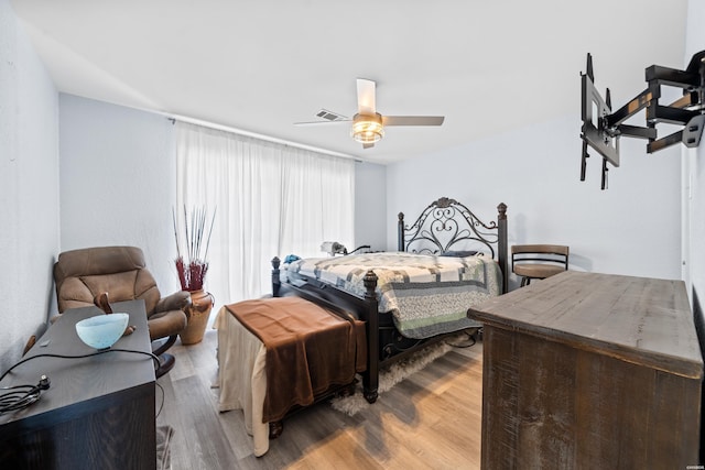 bedroom with ceiling fan, wood finished floors, and visible vents