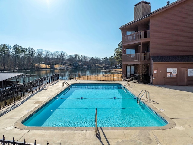 community pool with a patio, a water view, and fence