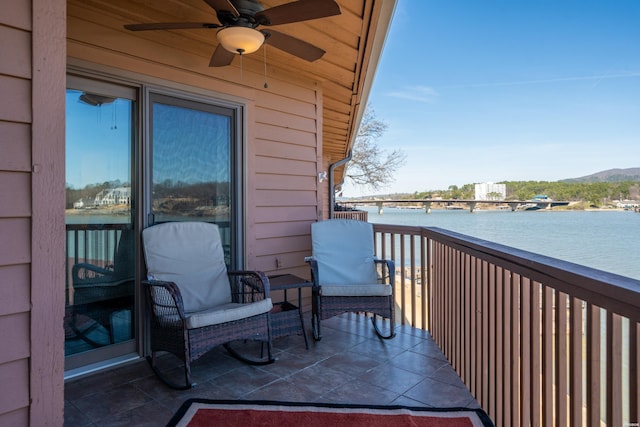 balcony with a water view and a ceiling fan