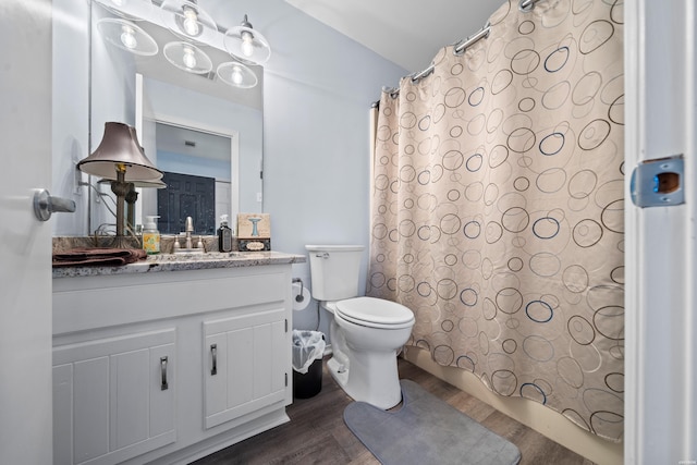 full bath featuring toilet, shower / tub combo with curtain, wood finished floors, and vanity