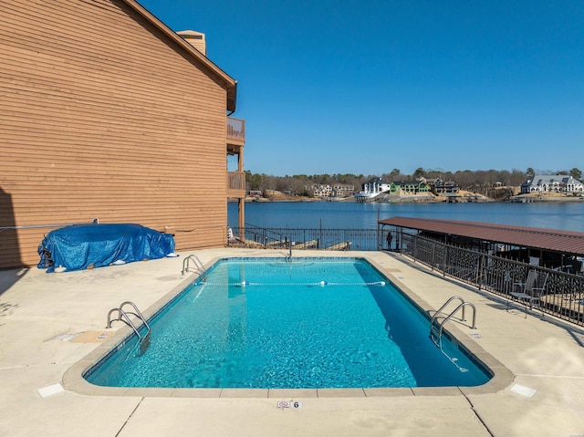 community pool featuring a patio, a water view, and fence