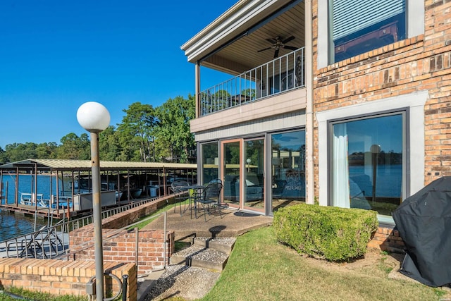 exterior space with a water view, grilling area, ceiling fan, a balcony, and a dock