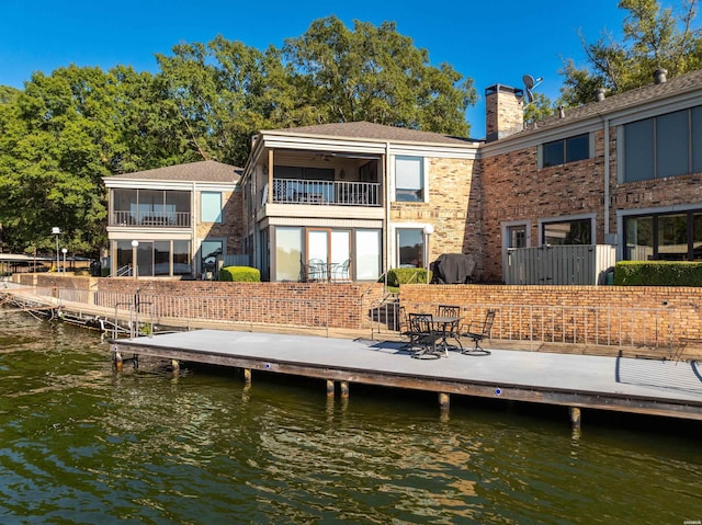 back of house featuring a sunroom, a water view, and a balcony