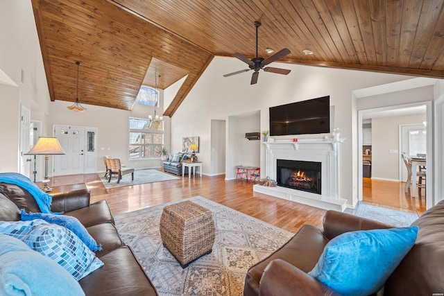 living area with wooden ceiling, ceiling fan, high vaulted ceiling, a lit fireplace, and wood finished floors