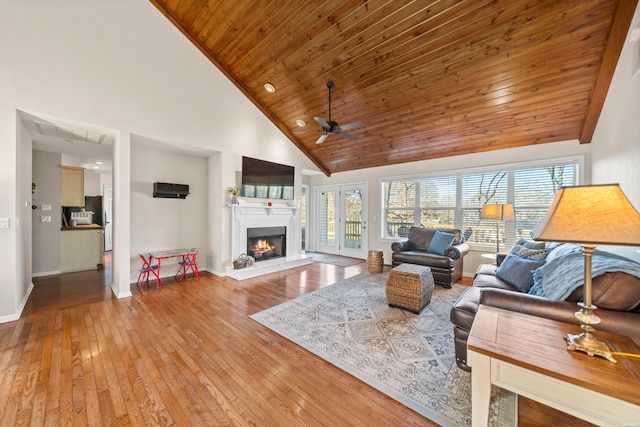 living area with wood ceiling, light wood-style flooring, a ceiling fan, baseboards, and a warm lit fireplace