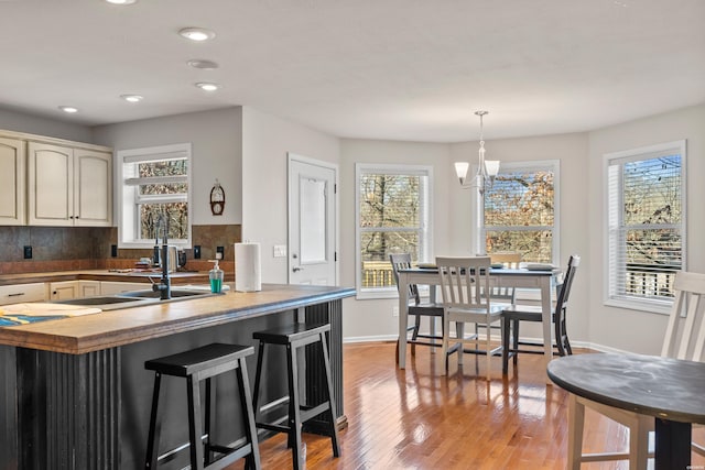 kitchen with an inviting chandelier, a wealth of natural light, light wood-style flooring, and baseboards