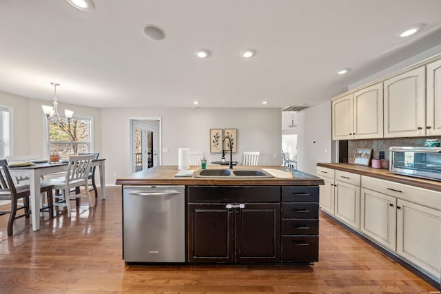 kitchen featuring a sink, cream cabinetry, stainless steel dishwasher, wooden counters, and a notable chandelier