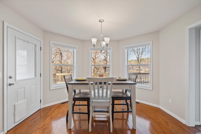 dining room with a notable chandelier, baseboards, and wood finished floors