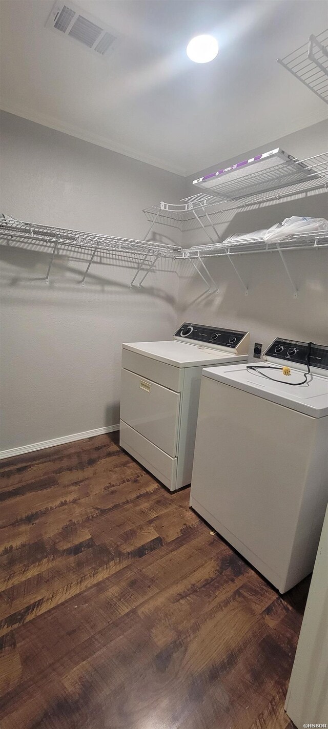 clothes washing area with laundry area, visible vents, washer and clothes dryer, and dark wood-type flooring