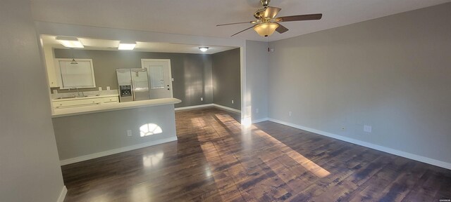 spare room with a ceiling fan, baseboards, dark wood-style flooring, and a sink