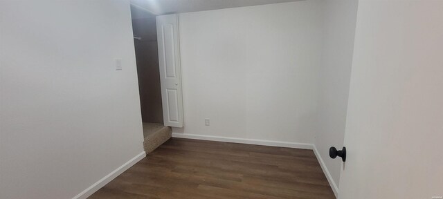 spare room with dark wood-type flooring and baseboards