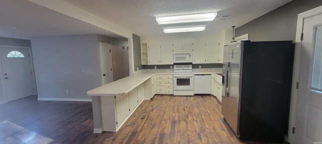 kitchen with white appliances, dark wood-style flooring, a peninsula, light countertops, and a textured ceiling