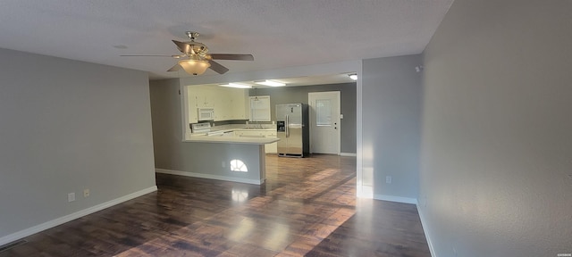 kitchen with dark wood finished floors, stainless steel appliances, light countertops, white cabinetry, and baseboards