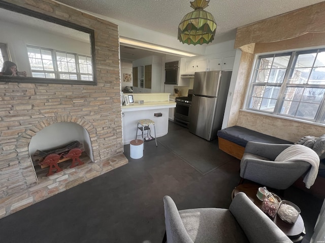 living area featuring a fireplace with raised hearth, concrete floors, and a textured ceiling