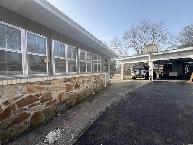 view of side of home featuring a carport, stone siding, and driveway