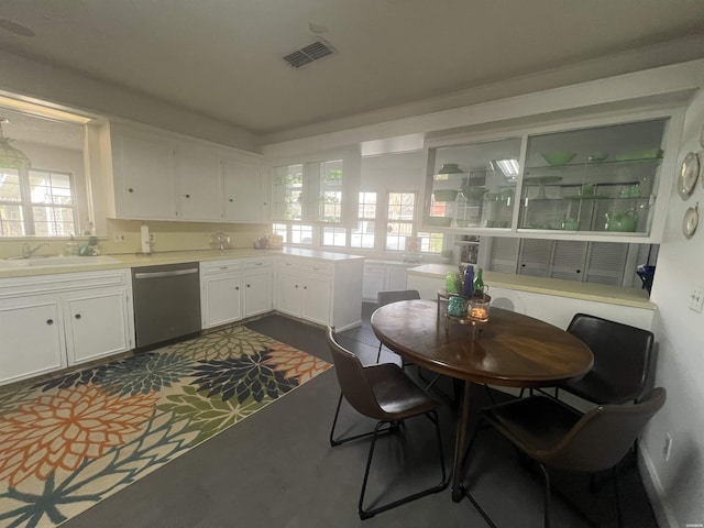 kitchen featuring light countertops, visible vents, stainless steel dishwasher, white cabinetry, and a sink