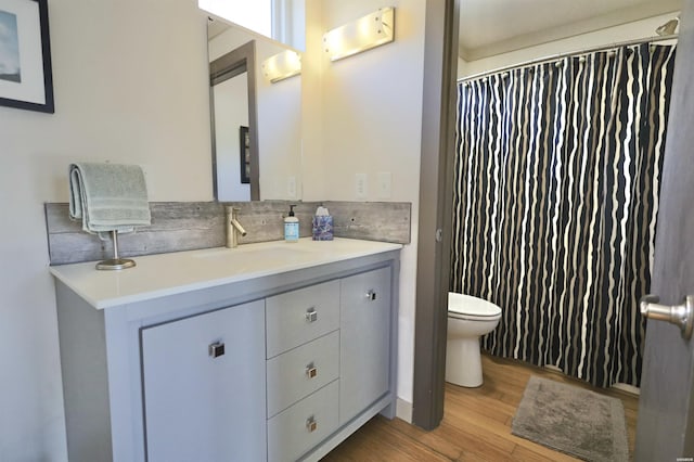 full bathroom featuring toilet, tasteful backsplash, wood finished floors, and vanity